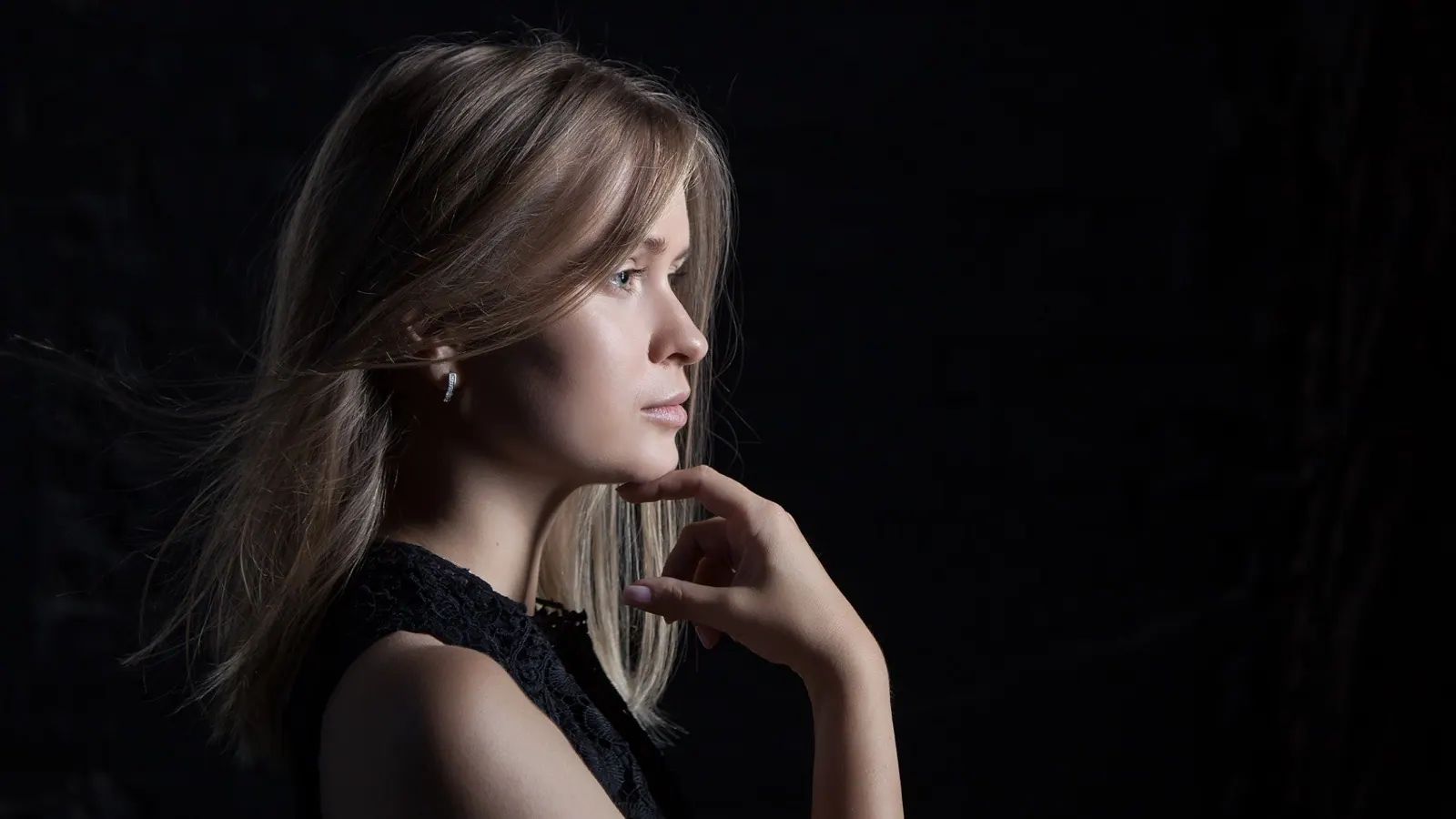 Krystyna in low-key studio light, chin resting on her hand