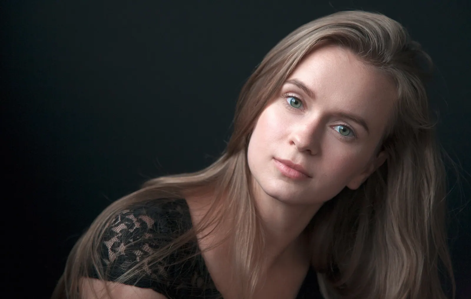 Krystyna in soft side light against a black background, looking into the camera