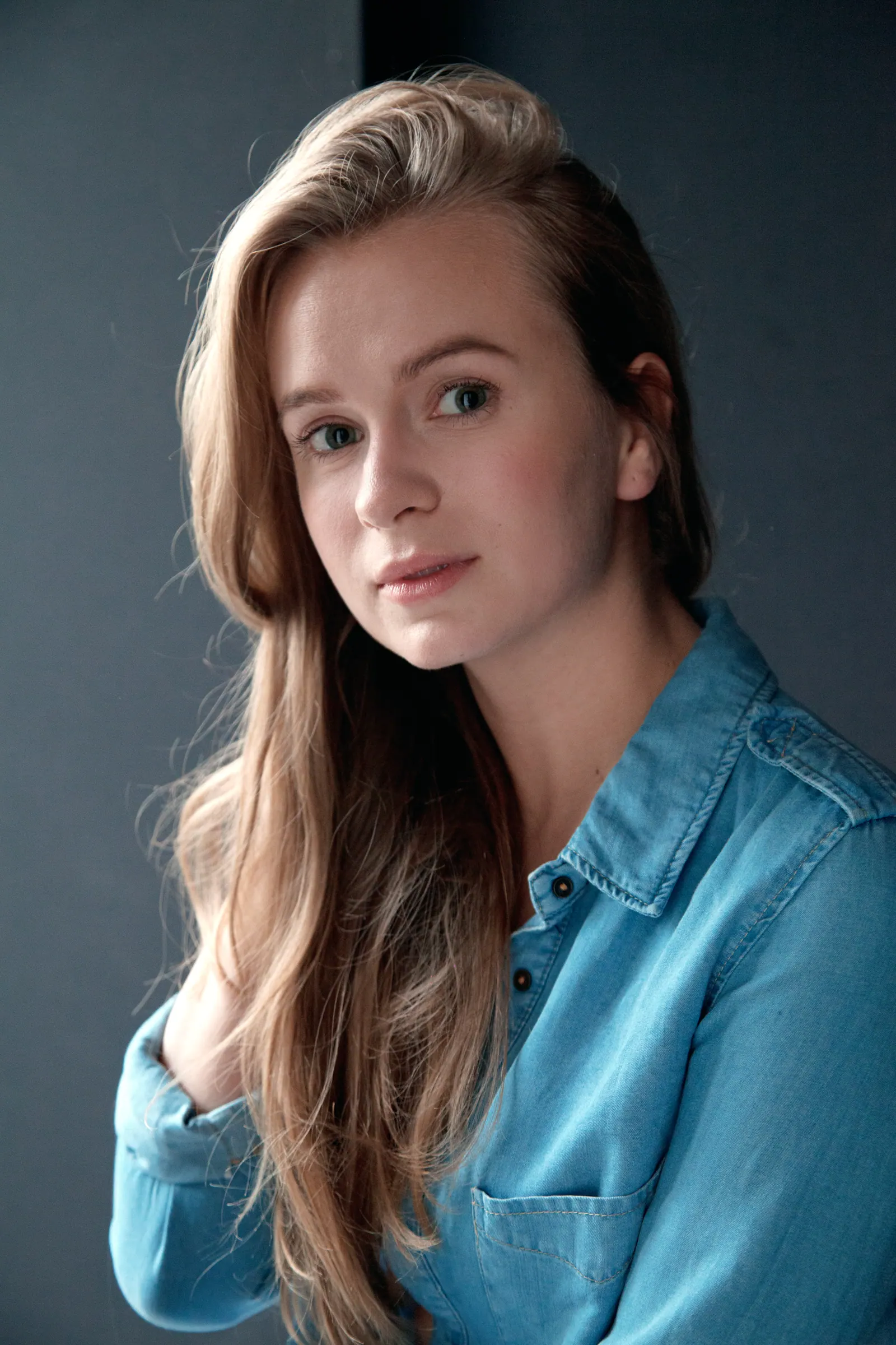 Headshot of Krystyna in a denim shirt against a blue-grey backdrop