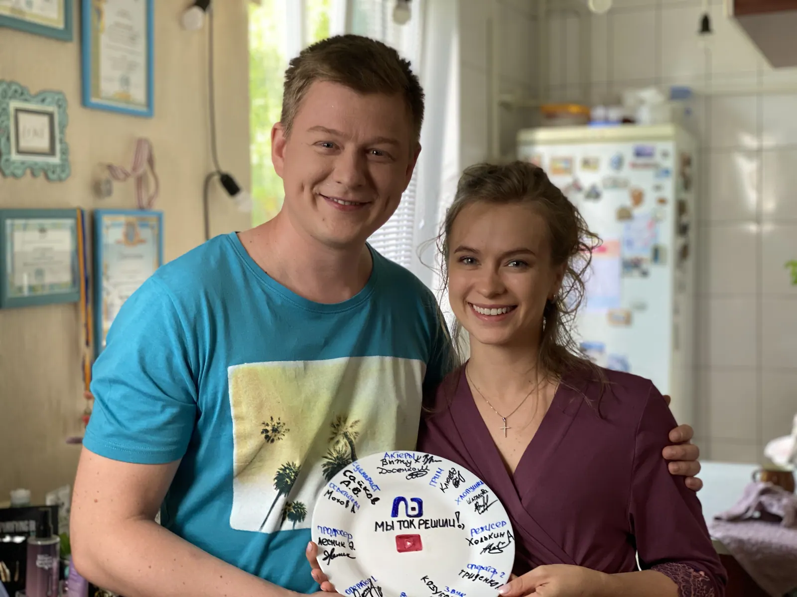 Krystyna and a scene partner on set in a kitchen, holding a decorated plate