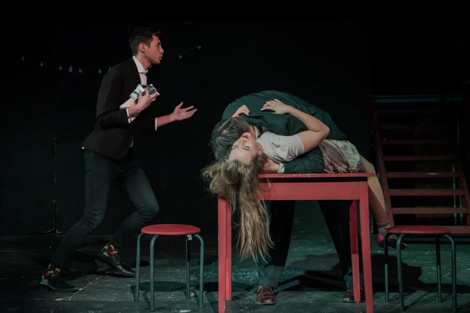A dramatic moment on stage with a scene partner at a red table